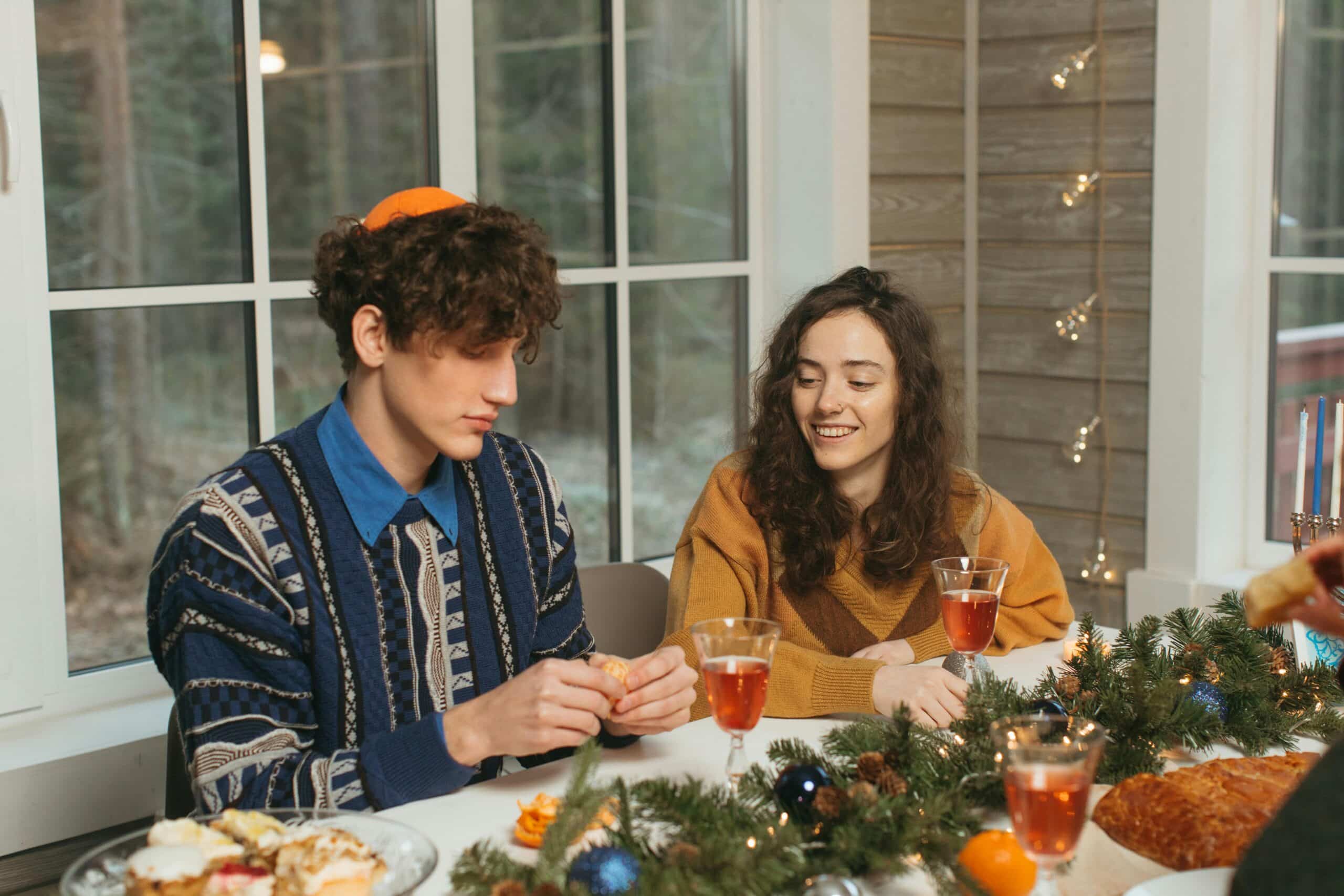 Friends enjoying a cozy Hanukkah dinner with traditional foods and decorations.